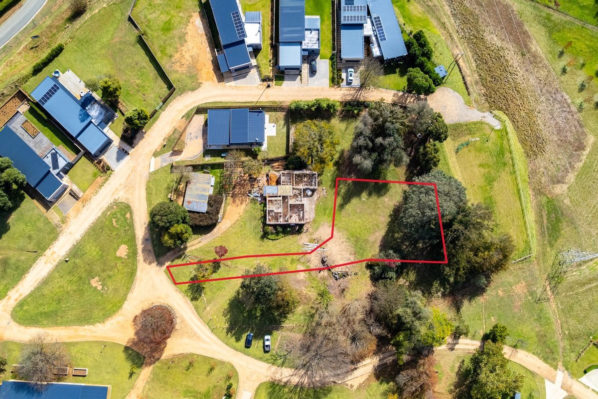 Aerial view of a vacant residential plot featuring established trees and surrounding rural residential infrastructure.