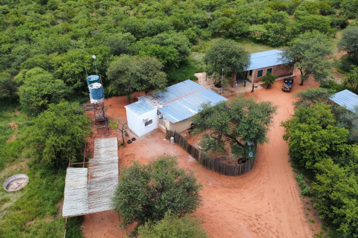 Aerial view of a rural farm property featuring multiple structures, a water tank tower, and natural bushveld surroundings.