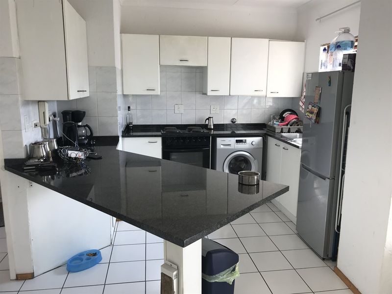 Functional kitchen featuring dark granite countertops, white cabinetry, built-in oven with hob, and integrated laundry plumbing connections.