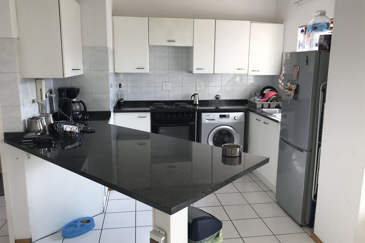 Functional kitchen featuring dark granite countertops, white cabinetry, built-in oven with hob, and integrated laundry plumbing connections.