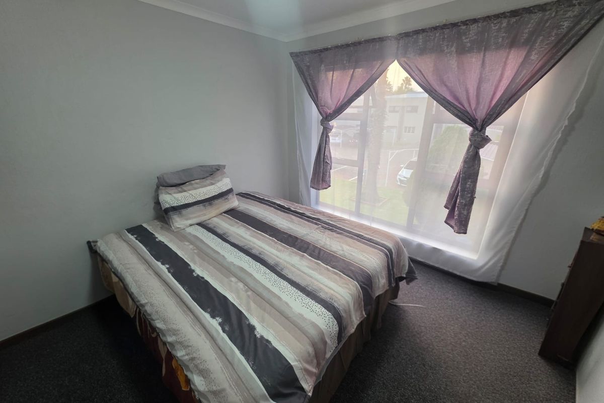 A bedroom featuring carpeted flooring and a large window providing natural light.
