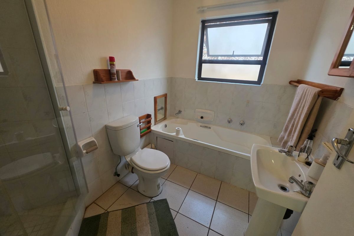 A functional bathroom featuring a shower enclosure, bathtub, and pedestal basin with tiled finishes throughout.