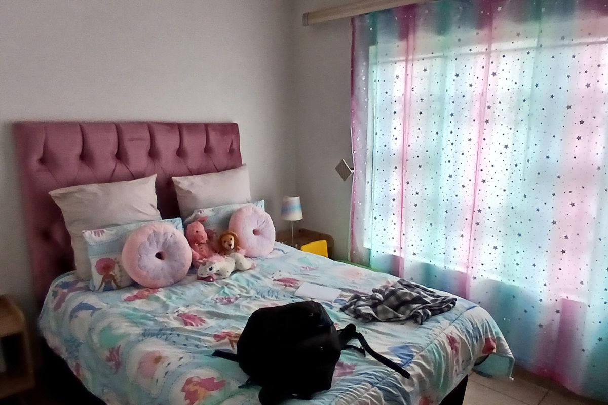 A bedroom featuring a large window with curtain tracks and tiled flooring.