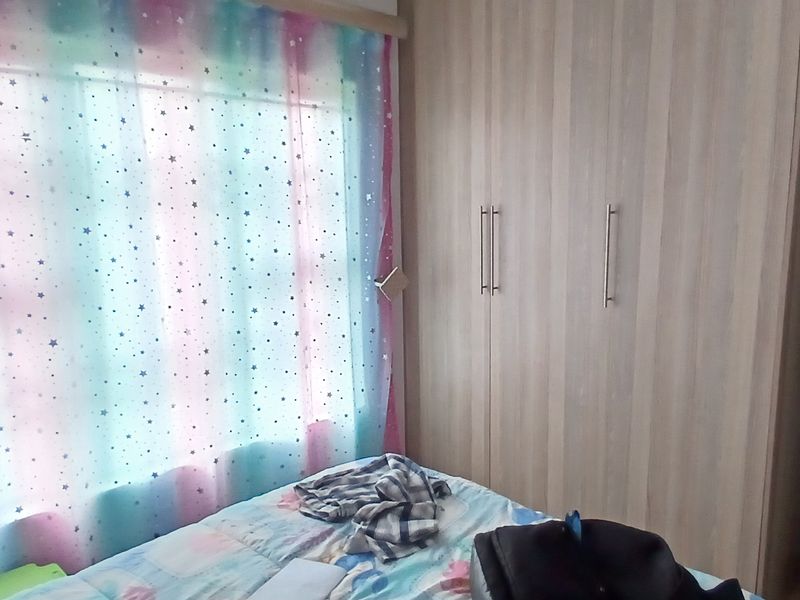 A bedroom featuring built-in wooden wardrobes and a window with natural light.