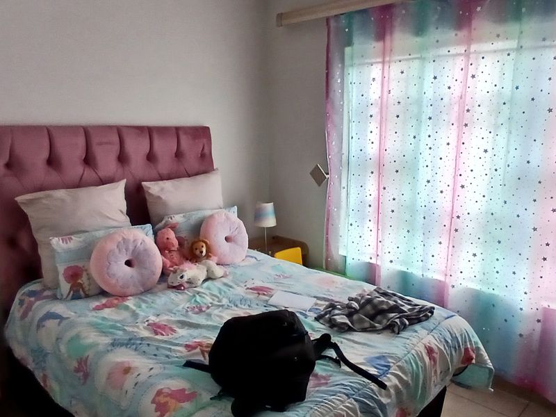A bedroom featuring a large window with curtain tracks and tiled flooring.