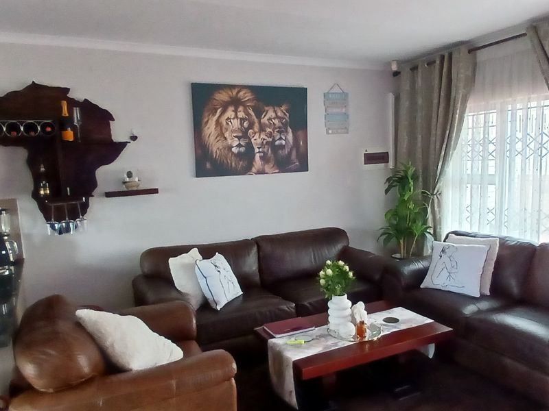 An open-plan living area featuring a compact kitchen with built-in cabinetry and a comfortable lounge space with large windows and security gates.