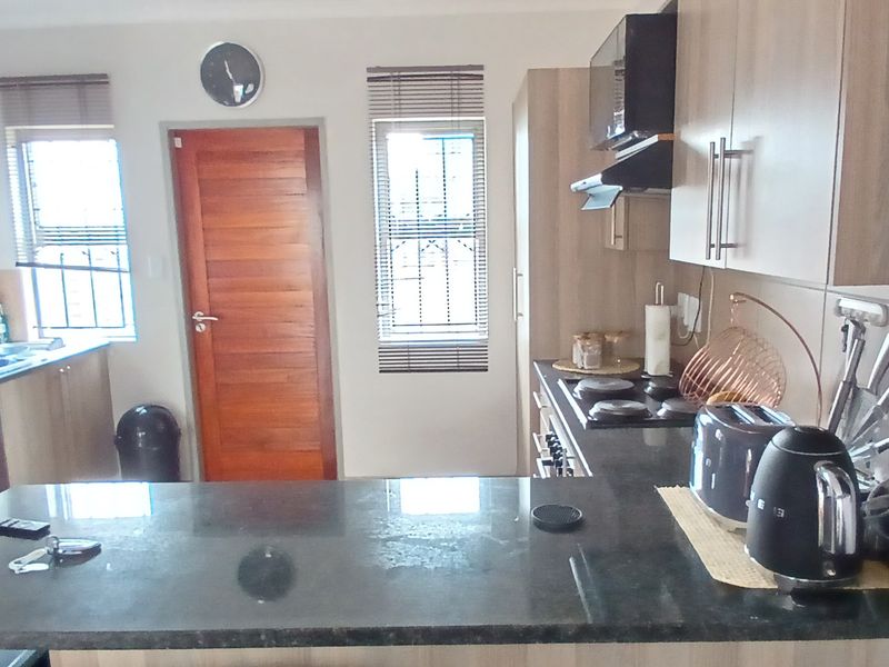 Modern kitchen featuring granite countertops, built-in cabinetry, a hob, and an extractor fan, with a functional layout and natural light.