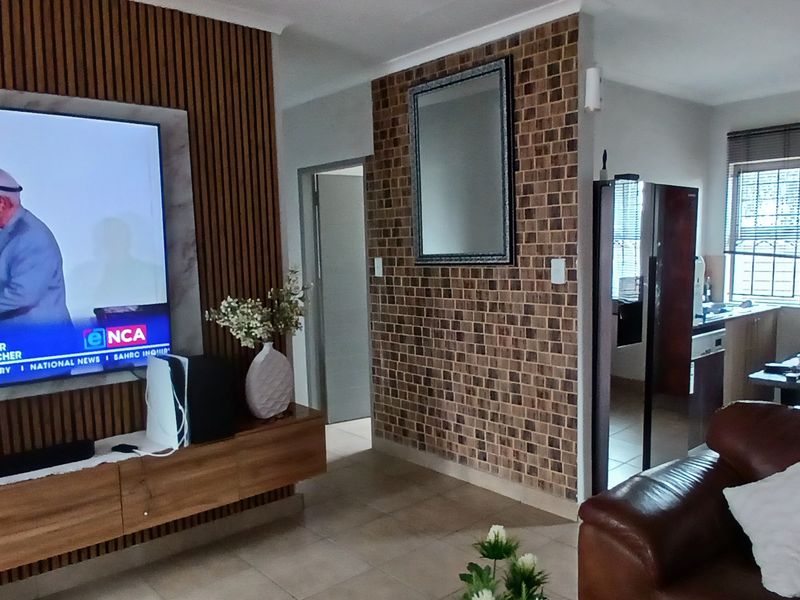Open-plan living area featuring a modern slatted wood feature wall, tiled flooring, and a seamless transition into the adjacent kitchen space.