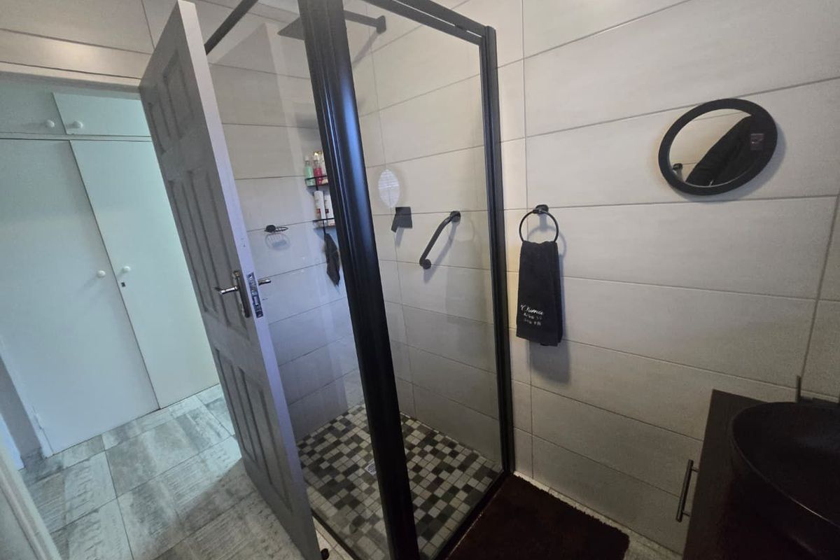 Modern bathroom featuring a walk-in shower with a black frame, tiled walls, and a contemporary vanity unit.