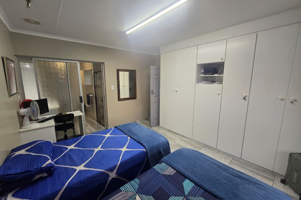 A bedroom featuring built-in cupboards, tiled flooring, and an en-suite bathroom access.
