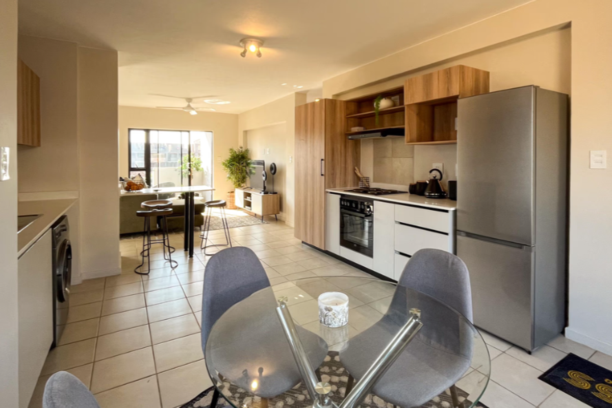 Modern open-plan kitchen and dining area featuring contemporary cabinetry, integrated appliances, tiled flooring, and seamless flow into the adjacent living space.