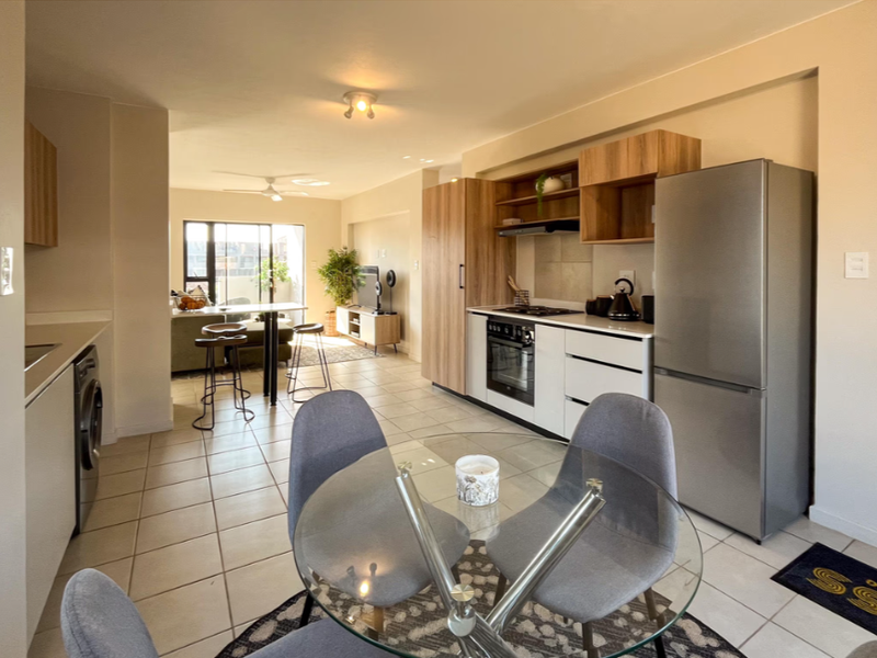 Modern open-plan kitchen and dining area featuring contemporary cabinetry, integrated appliances, tiled flooring, and seamless flow into the adjacent living space.