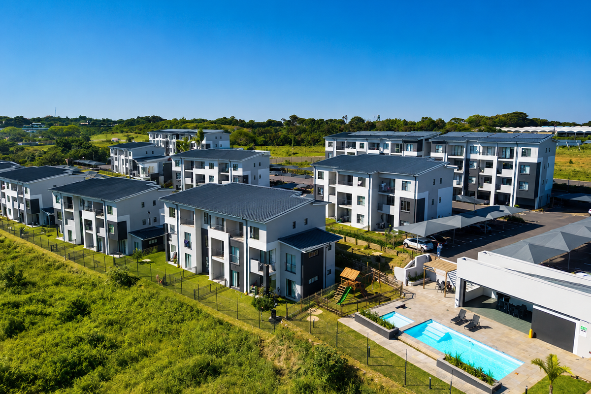 Aerial view of a modern townhouse complex featuring multiple residential blocks, a communal swimming pool, and covered parking facilities.