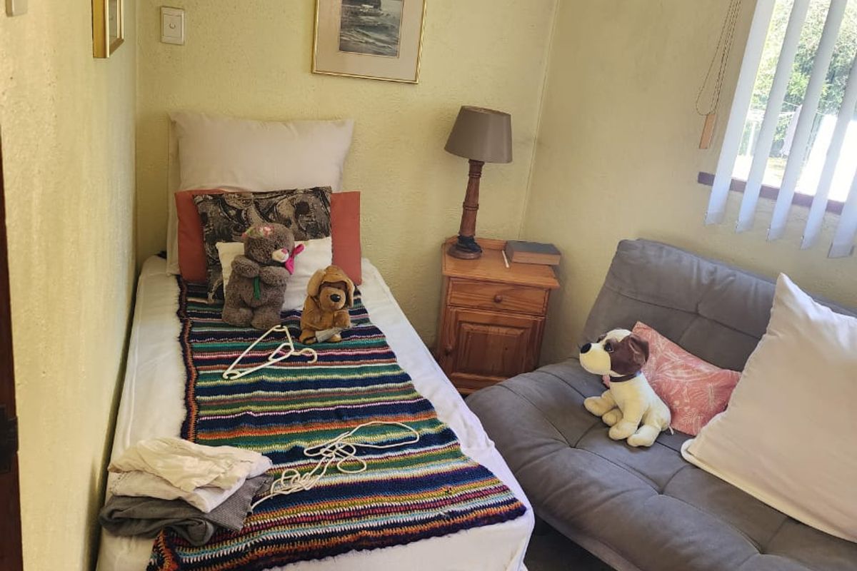 A compact bedroom featuring neutral wall finishes, vertical blinds, and carpeted flooring, suitable as a guest room or study.