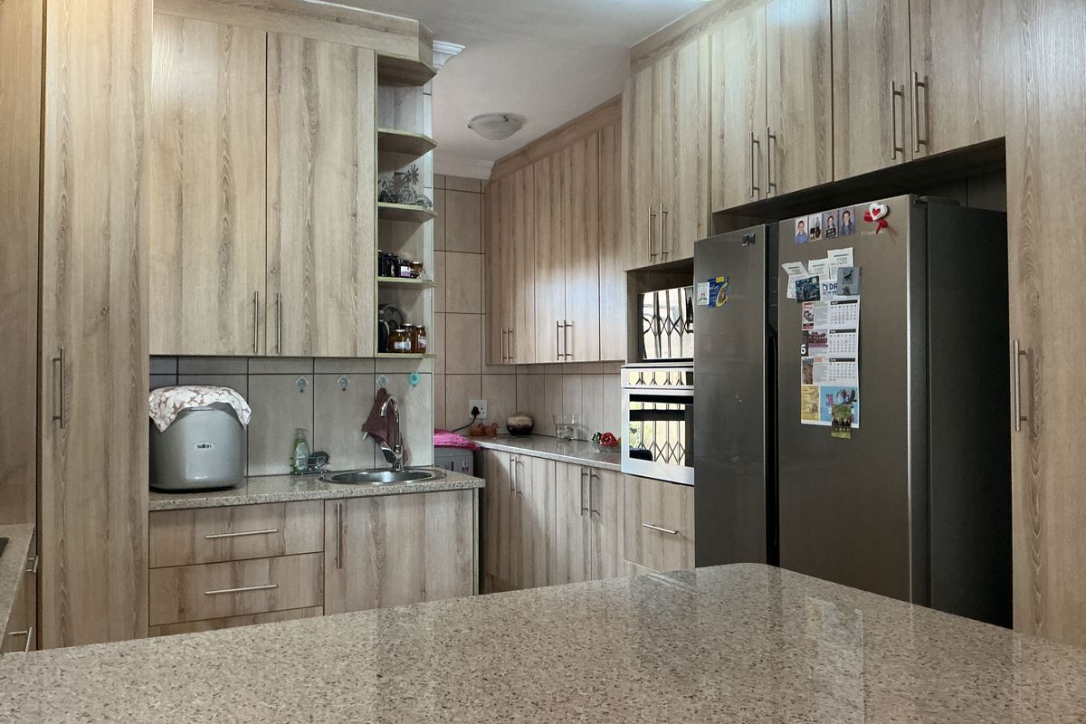 A functional kitchen featuring light wood-grain cabinetry, granite countertops, a built-in oven, and tiled backsplash, offering ample storage and workspace.