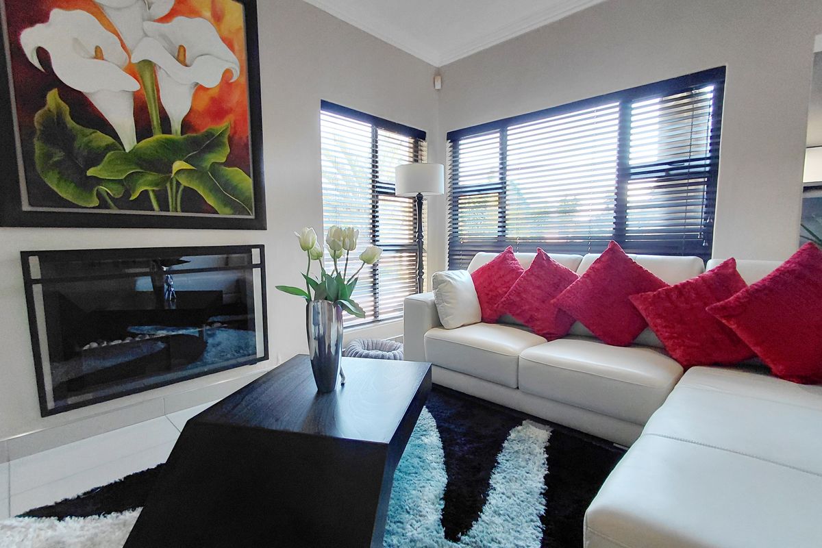A bright and comfortable living room featuring a built-in fireplace and large windows with fitted blinds, creating a welcoming atmosphere.