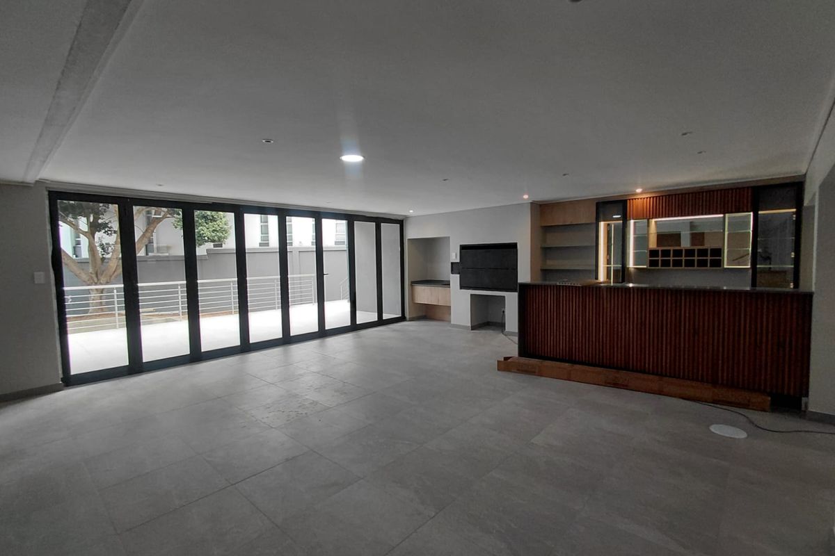 Spacious open-plan living area featuring a built-in bar, indoor braai, and large stacking doors leading to an outdoor patio.