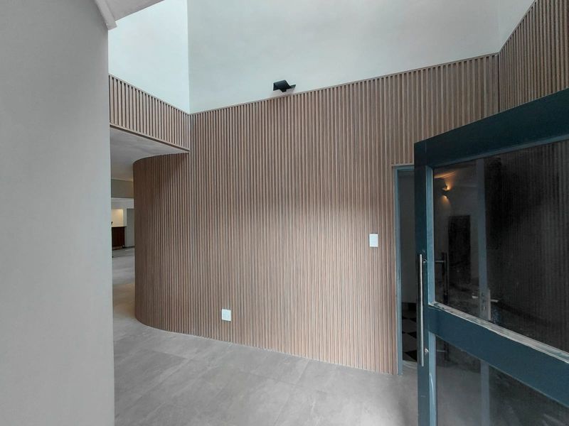 Modern entrance hall featuring high double volume ceilings, contemporary timber slat wall paneling, and large format floor tiles.
