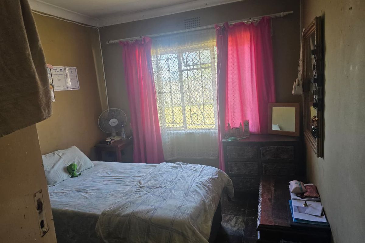A bedroom featuring a window with security bars, coved ceiling, and tiled flooring.