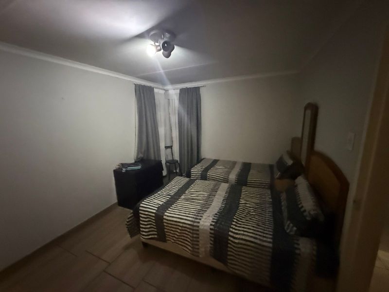 A bedroom featuring tiled flooring, neutral walls, and a ceiling-mounted light fixture.