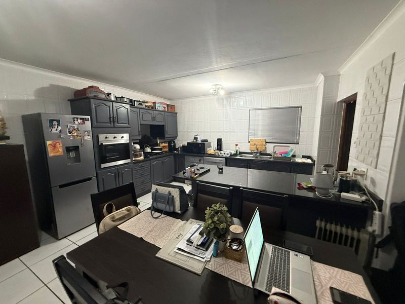 Open-plan kitchen featuring dark cabinetry, granite countertops, a built-in oven, and a central island, seamlessly flowing into the dining area.