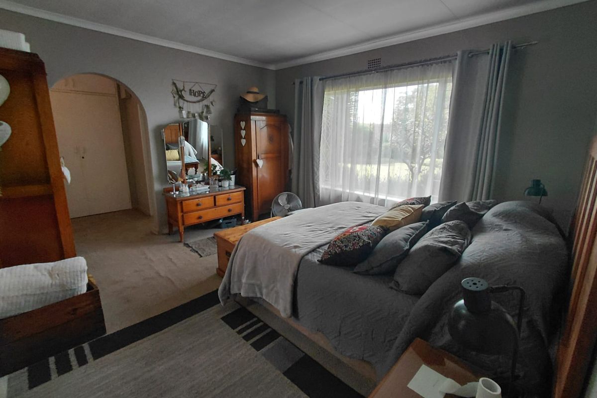 A spacious bedroom featuring an arched entryway, large window with natural light, and neutral wall tones.