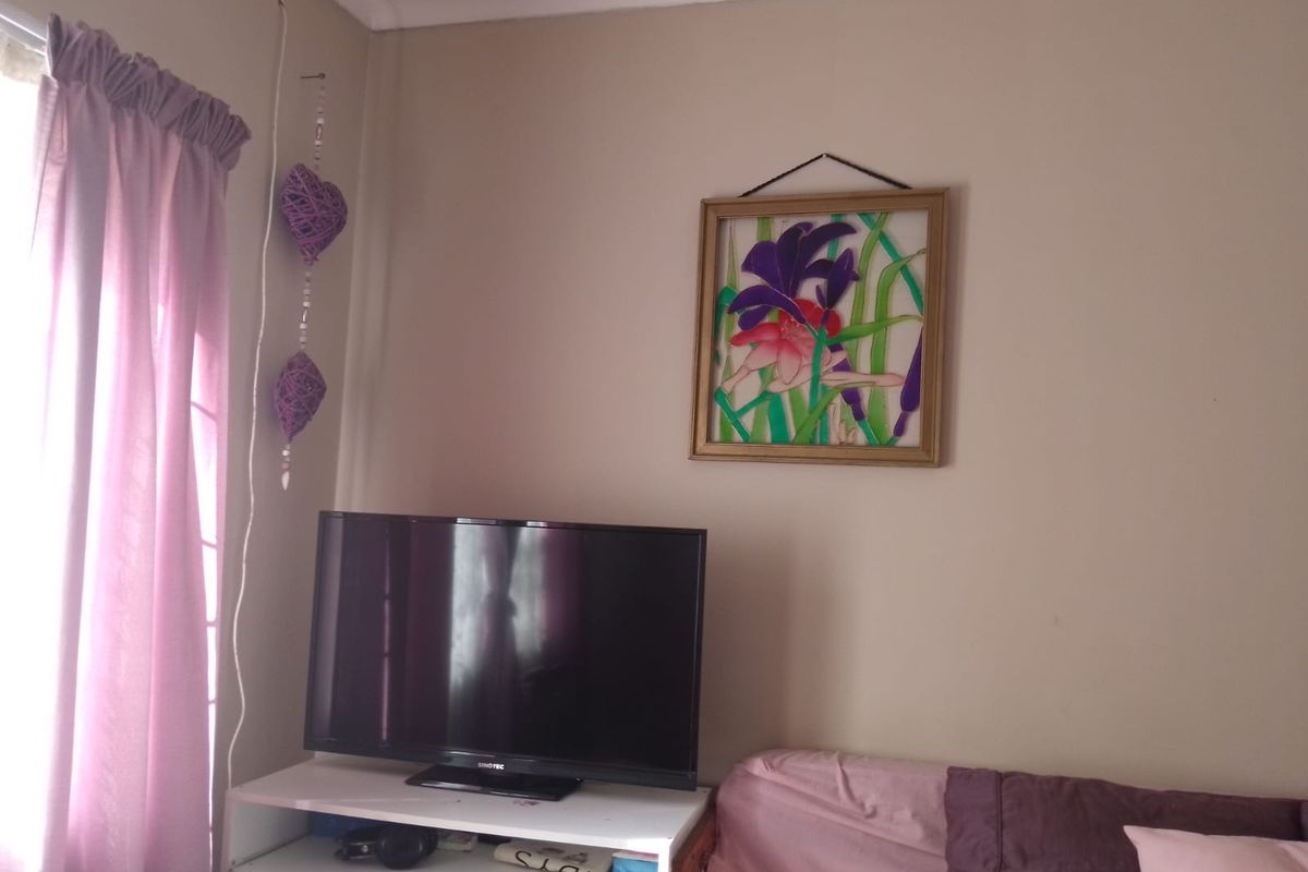 A view of a living room corner featuring neutral wall paint, a window with curtains, and space for a television unit.