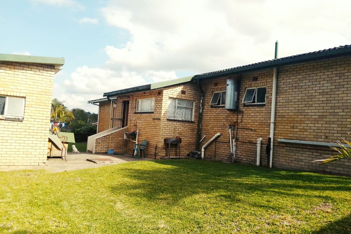 Rear view of the property featuring a brick facade, lawn area, and external utility connections.