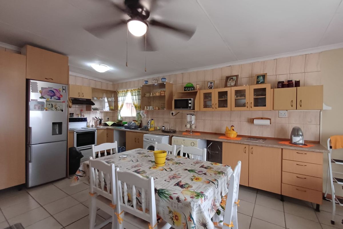 A functional kitchen featuring laminate cabinetry, tiled backsplash, ceramic flooring, and a ceiling fan, offering a practical layout for daily meal preparation.