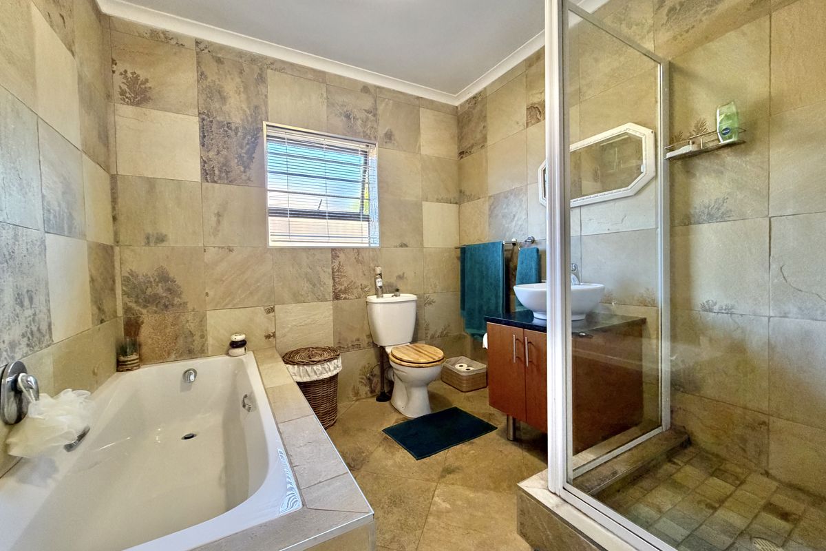A functional bathroom featuring a built-in bathtub, a separate glass-enclosed shower, a vanity cabinet with a basin, and a toilet.