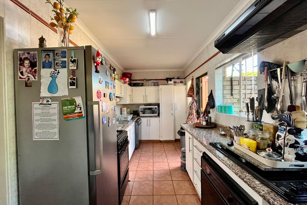 A functional galley-style kitchen featuring tiled flooring, laminate countertops, built-in cabinetry, and an integrated extractor fan.