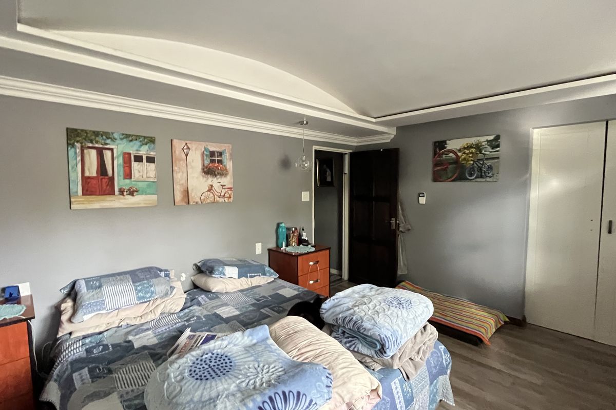 A spacious bedroom featuring a tray ceiling, laminate flooring, and built-in closet storage.