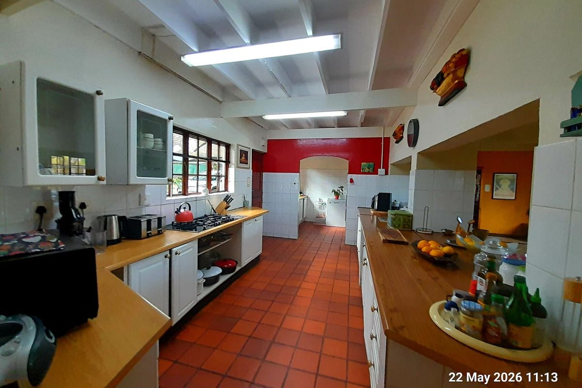 Spacious farmhouse kitchen featuring wooden countertops, tiled flooring, exposed beam ceilings, and ample built-in cabinetry with a functional layout.