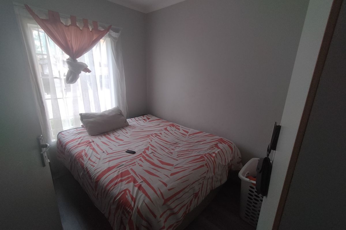 A compact bedroom featuring neutral wall finishes and a window, providing a functional sleeping space.