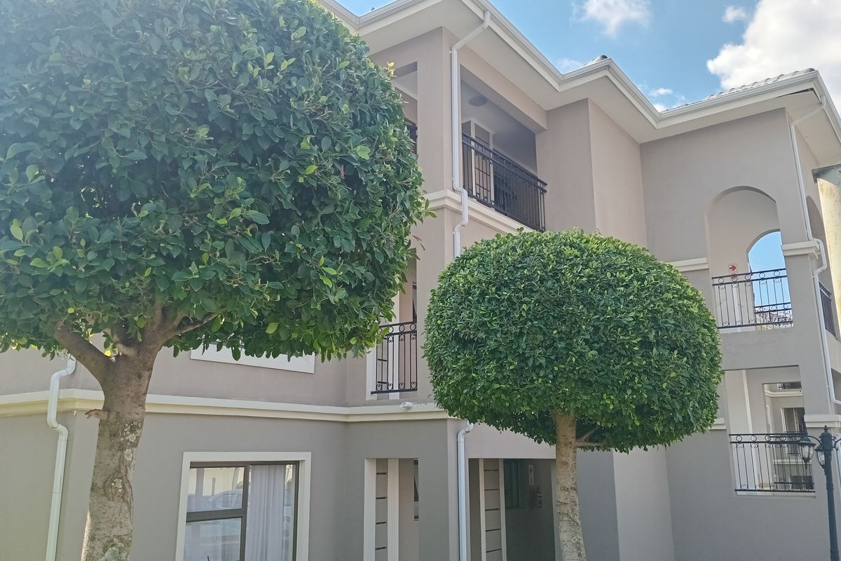 Exterior view of a multi-story townhouse featuring balconies with wrought iron railings and well-maintained facade finishes.
