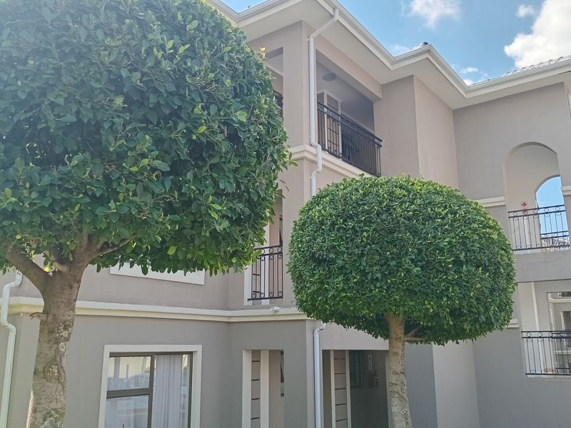 Exterior view of a multi-story townhouse featuring balconies with wrought iron railings and well-maintained facade finishes.