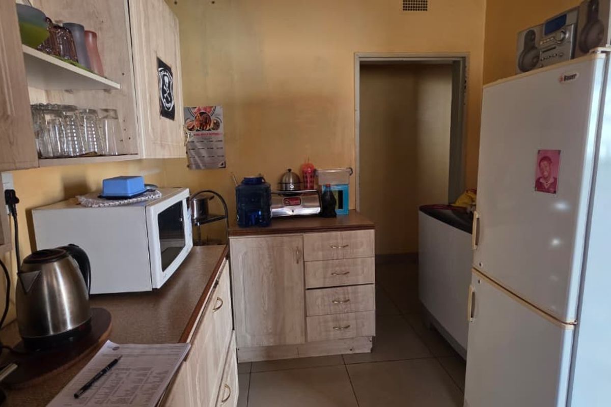 A functional kitchen area featuring light wood-look cabinetry, tiled flooring, and ample counter space for food preparation.