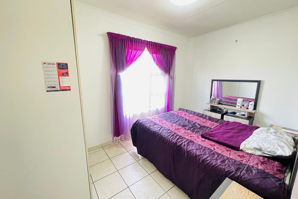 A functional bedroom featuring tiled flooring, built-in cupboard space, and a window with curtain fixtures.