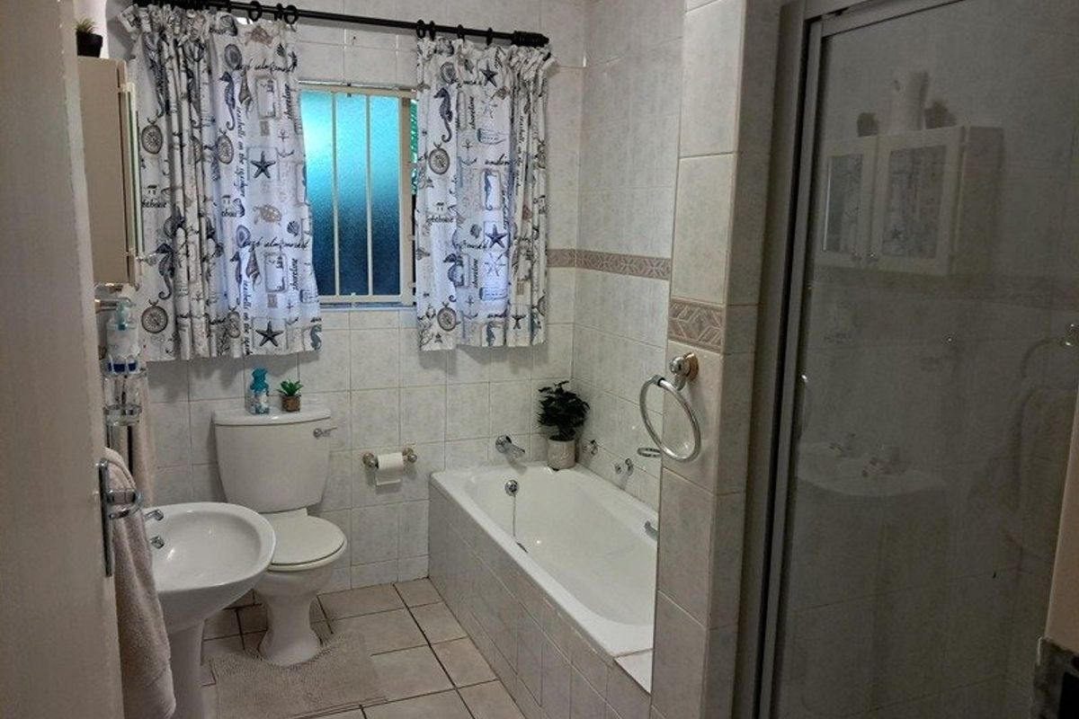 A functional bathroom featuring a pedestal basin, a built-in bathtub, and a separate glass-enclosed shower with tiled walls and flooring.