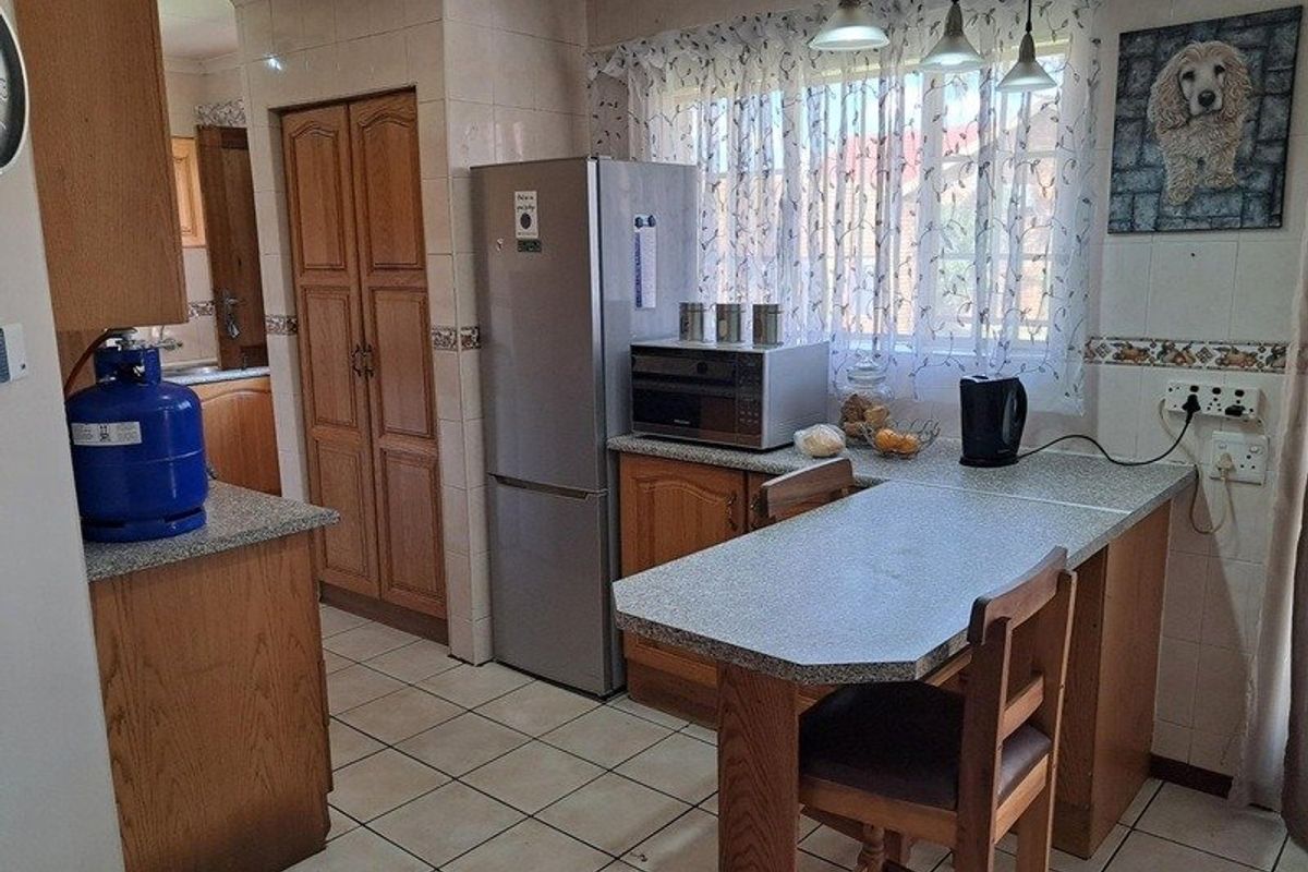 A functional kitchen featuring wooden cabinetry, tiled flooring, and a breakfast nook area with integrated counter space.