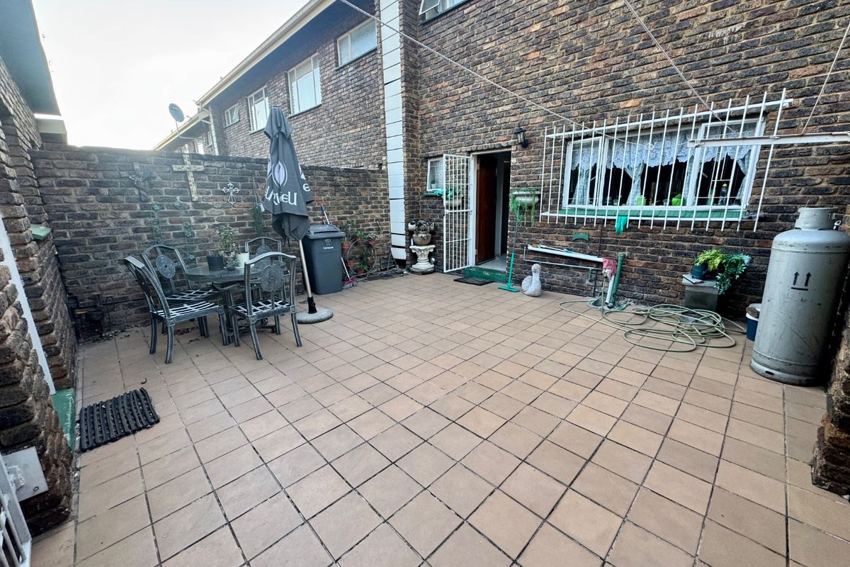 A private rear courtyard featuring paved flooring, enclosed by brick boundary walls, providing direct access to the townhouse interior.