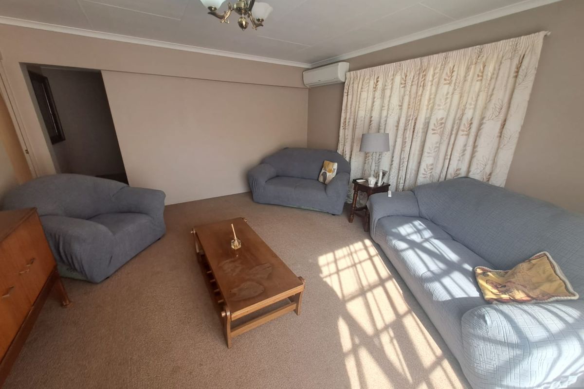 A living room featuring carpet flooring, a split-system air conditioner, and a central ceiling light fixture.
