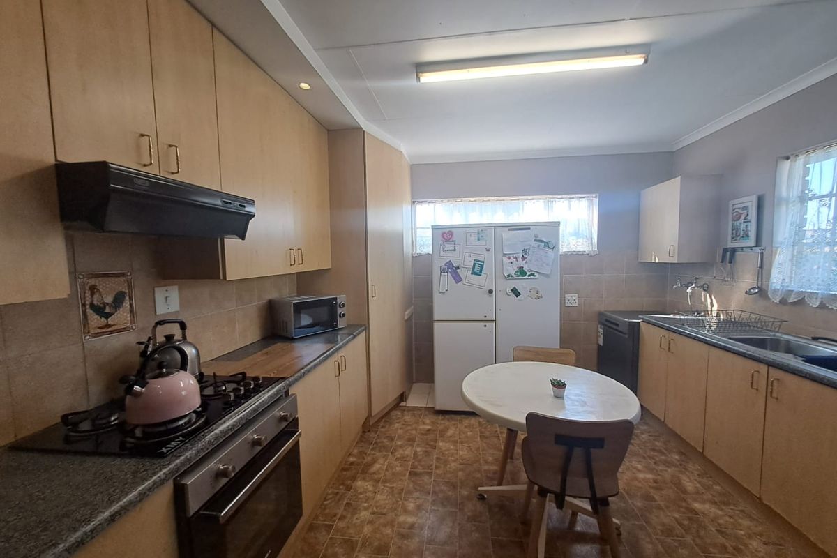A functional kitchen featuring light wood-finish cabinetry, a gas hob with extractor, built-in oven, and tiled backsplash with ample counter space.