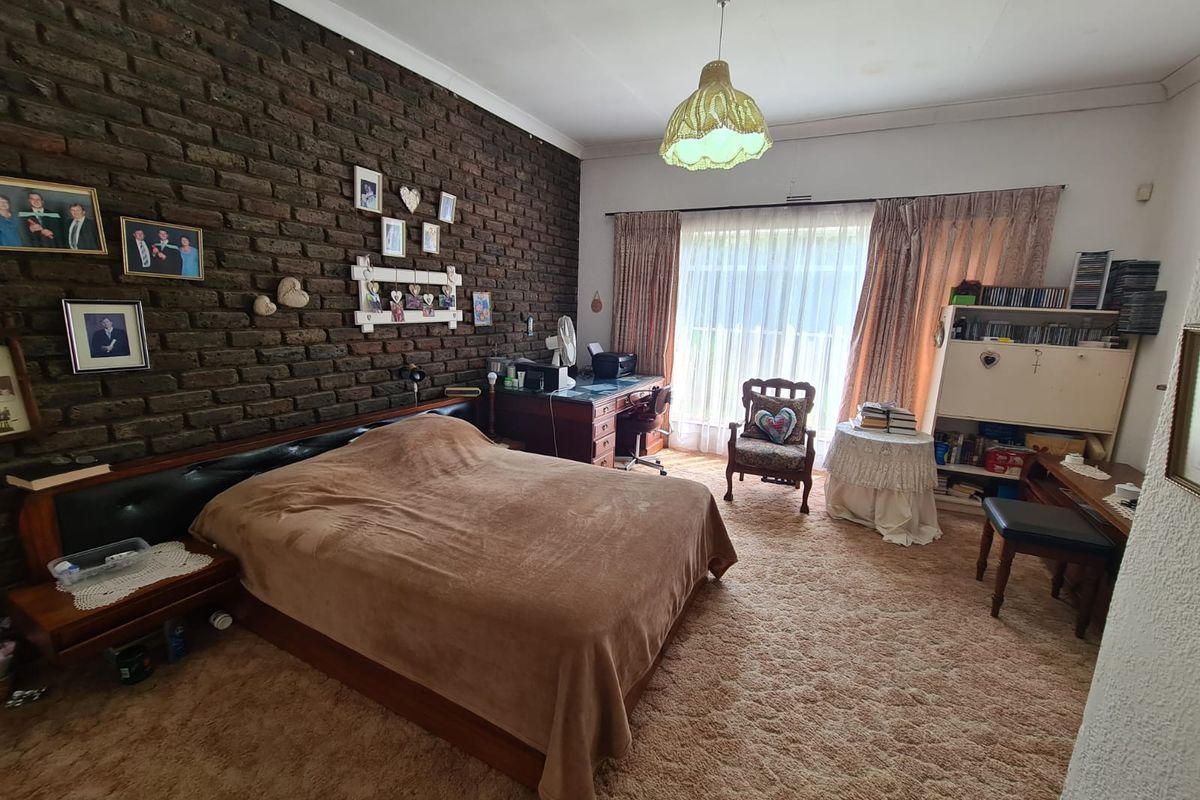 Spacious bedroom featuring a prominent exposed brick feature wall, carpeted flooring, and large sliding glass doors providing natural light.