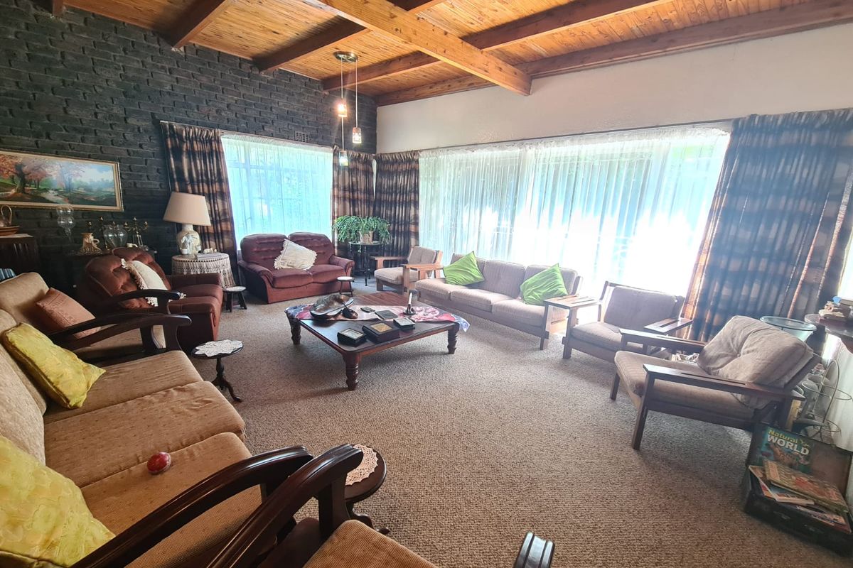 Spacious living room featuring an exposed timber beam ceiling, a dark brick feature wall, and large sliding glass doors providing ample natural light.