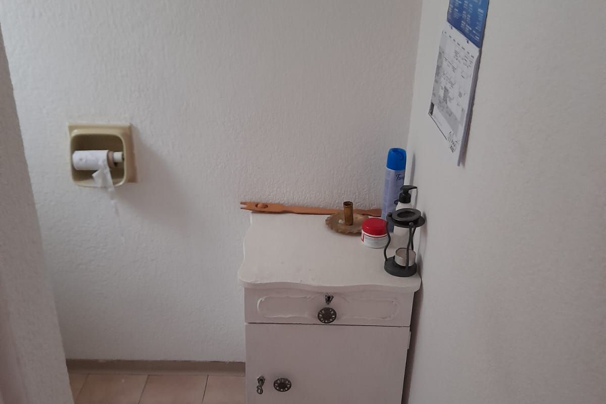 A small bathroom space featuring ceramic floor tiles and a recessed toilet paper holder.