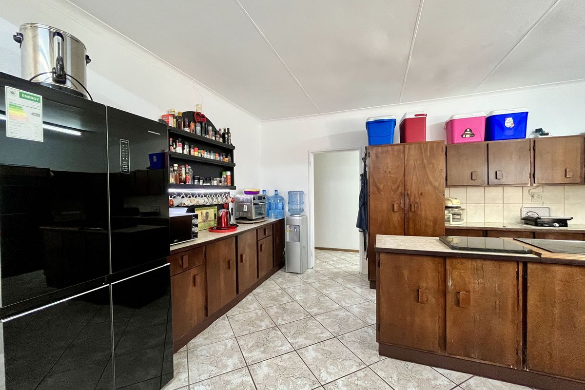 A dated kitchen featuring dark wood cabinetry, tiled flooring, and a functional layout with ample storage space.