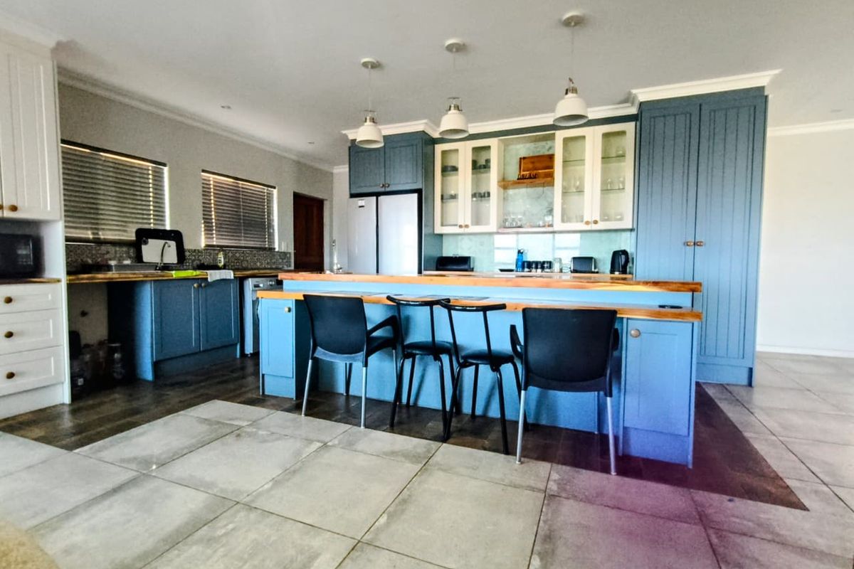 A spacious kitchen featuring blue cabinetry, a large central island with a wooden countertop, and integrated storage solutions.