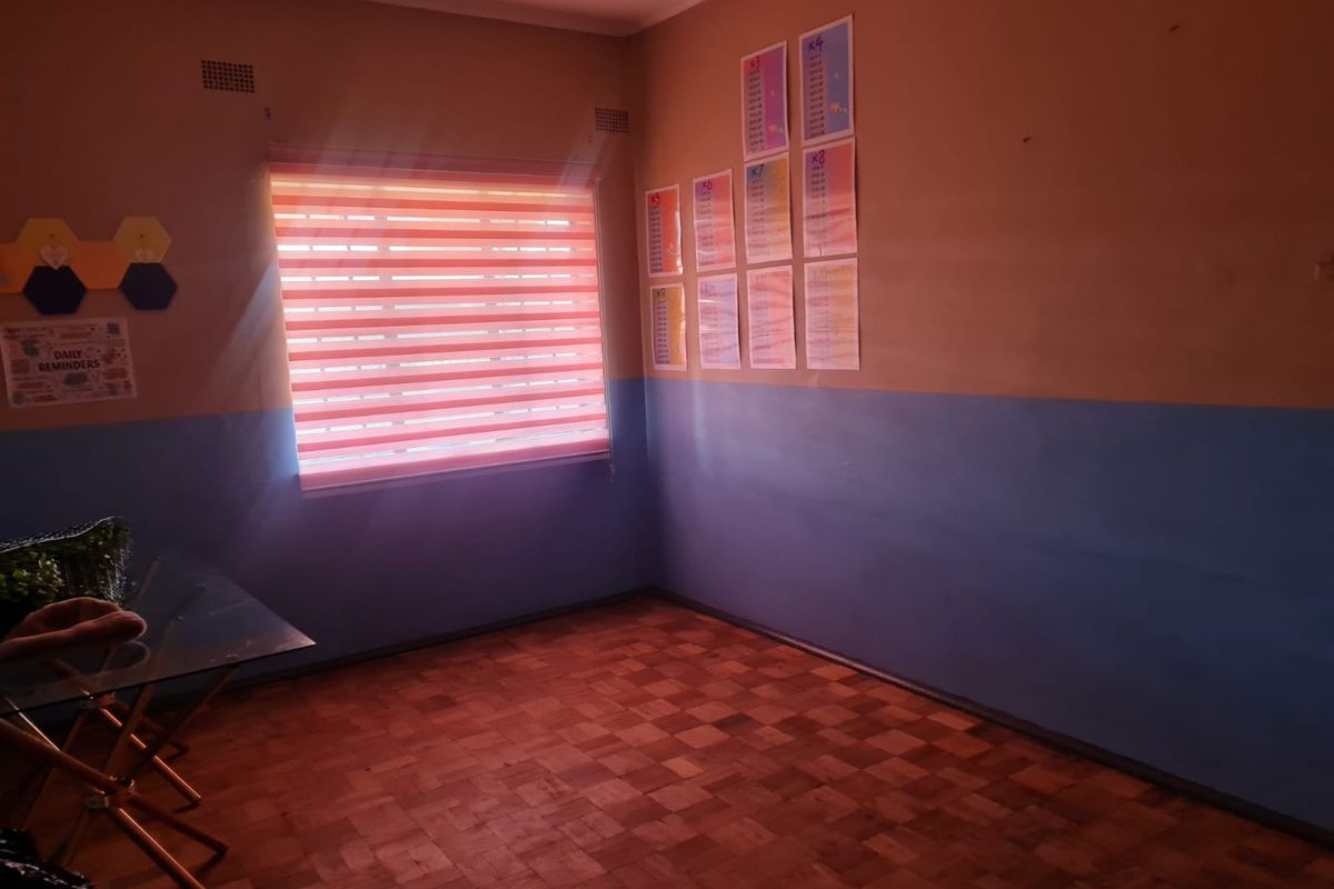 A bedroom featuring parquet flooring, a window with a roller blind, and two-tone wall paint.