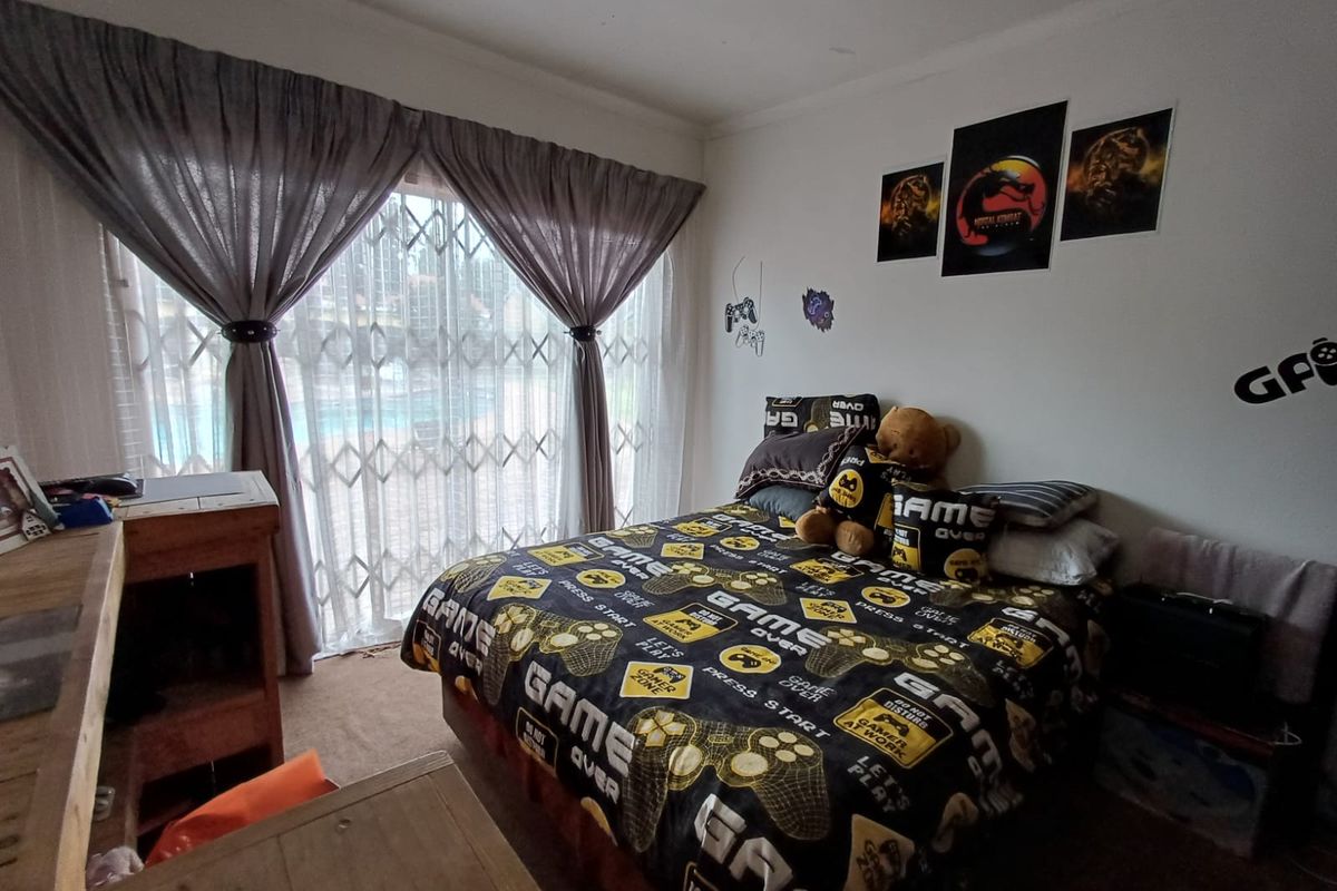A bedroom featuring a sliding glass door with security gate, providing natural light and access to the exterior.
